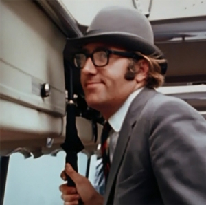 Resplendent in a smart gray blazer and striped tie, Mal Evans is already dressed for the role of Maxwell Edison as he rides the Magical Mystery Tour bus.